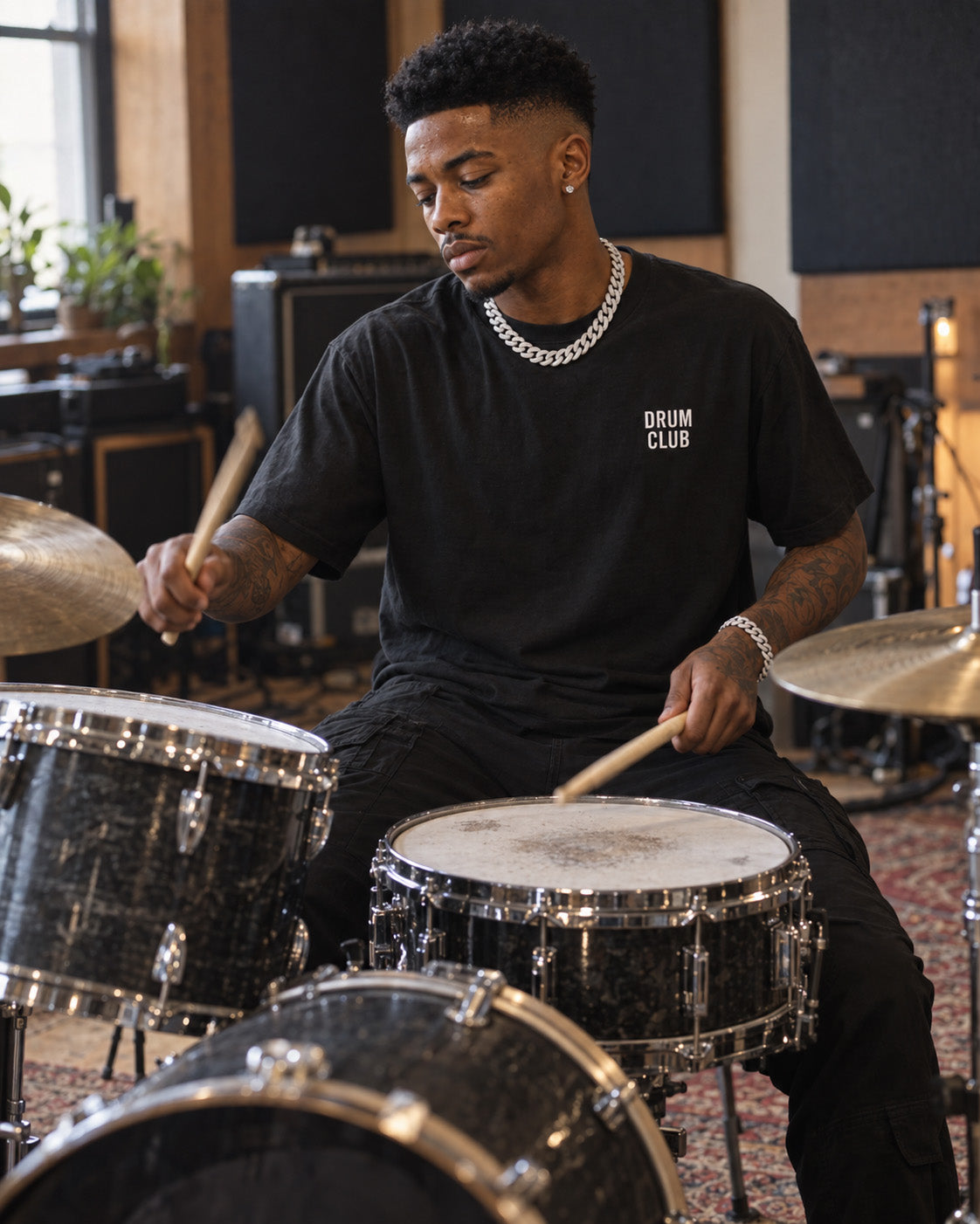 Drummer wearing a black DRUM CLUB Classic Tee while seated behind a drum kit.